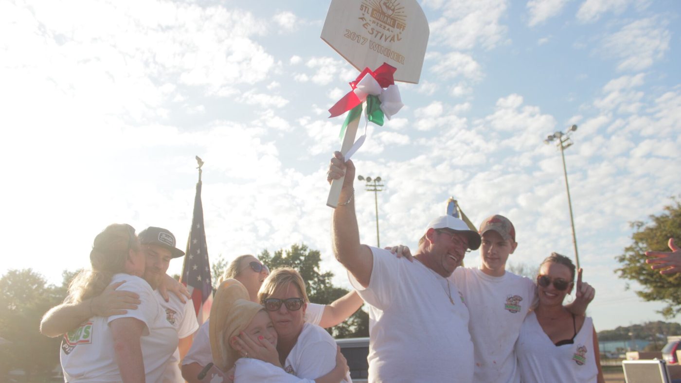 Winners celebrating with a flag at an outdoor festival