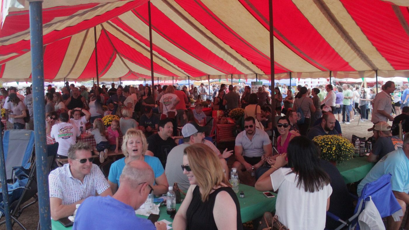 A packed festival tent with guests seated at tables